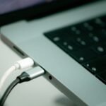 Laptop plugged in to a charger on a desk, a fix for laptop battery draining fast in Windows 11