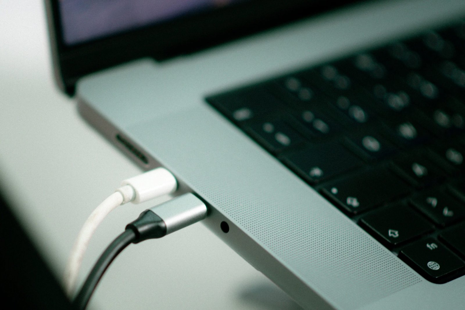 Laptop plugged in to a charger on a desk, a fix for laptop battery draining fast in Windows 11
